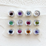 Sterling silver aurora pendants with birthstones garnet for January,  amethyst for February, aquamarine for March, diamond for April, emerald for May, moonstone for June, ruby for July, peridot for August, blue sapphire for September, pink tourmaline for October, citrine for November, and tanzanite for December